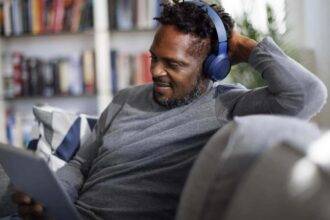 Smiling man with bluetooth headphones watching movie on digital tablet at home